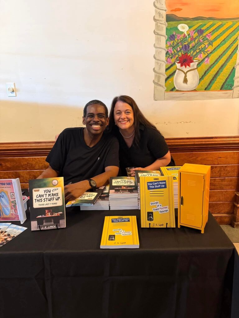 J.K. Lynch smiling with a supporter at his book signing table
